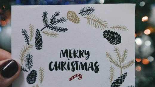 person holding beige and black floral merry christmas card